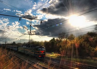 Cars on railroad tracks against sky during sunset