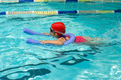 Girl with noodle swimming in pool