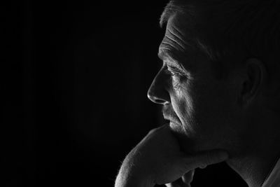 Profile view of thoughtful mature man against black background