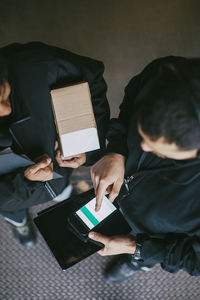 Female and male manual workers using mobile phone at warehouse