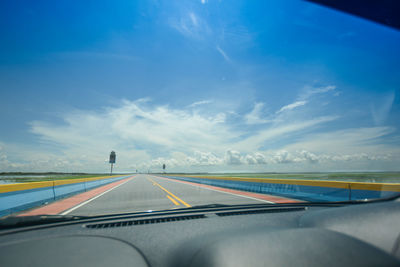 Road seen through car windshield against blue sky