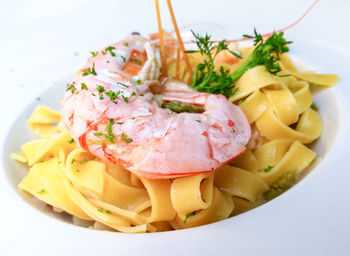 High angle view of tagliatelle and prawns garnished with cilantro served in bowl on table