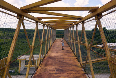 Rear view of boy walking on footbridge