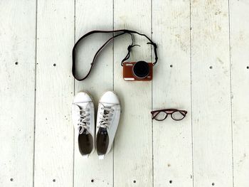 High angle view of shoes with camera and eyeglasses on wooden table