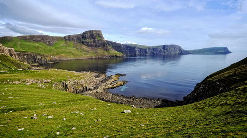 Scenic view of sea by cliff against sky