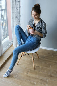 Millennial brown-haired girl drinking tea with cakes alone