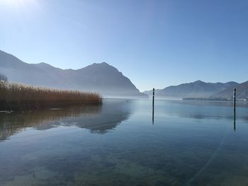 Scenic view of lake and mountains against clear blue sky