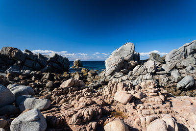 Panoramic view of rocks and sea against blue sky