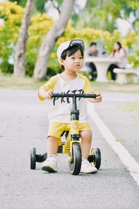 Portrait of boy riding push scooter on road