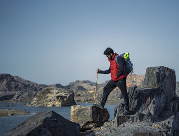 Man climbing rock on mountain against clear sky
