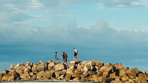 People standing on rock by sea against sky