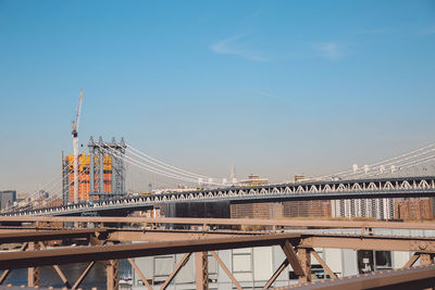 Manhattan bridge against blue sky on sunny day in city