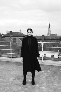 Full length portrait of smiling standing against building against sky