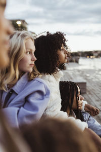 Female friends looking while sitting on pier