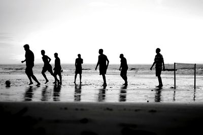 Silhouette people on beach against sky