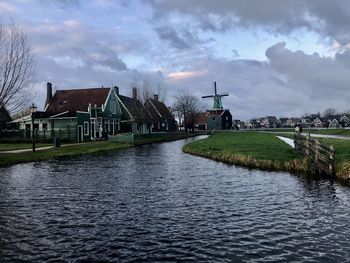 Houses by lake and buildings against sky