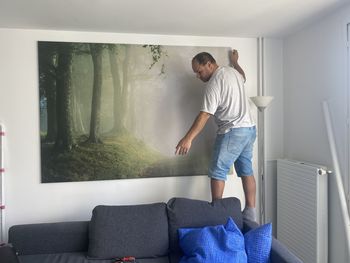 Full length of man standing on sofa at home