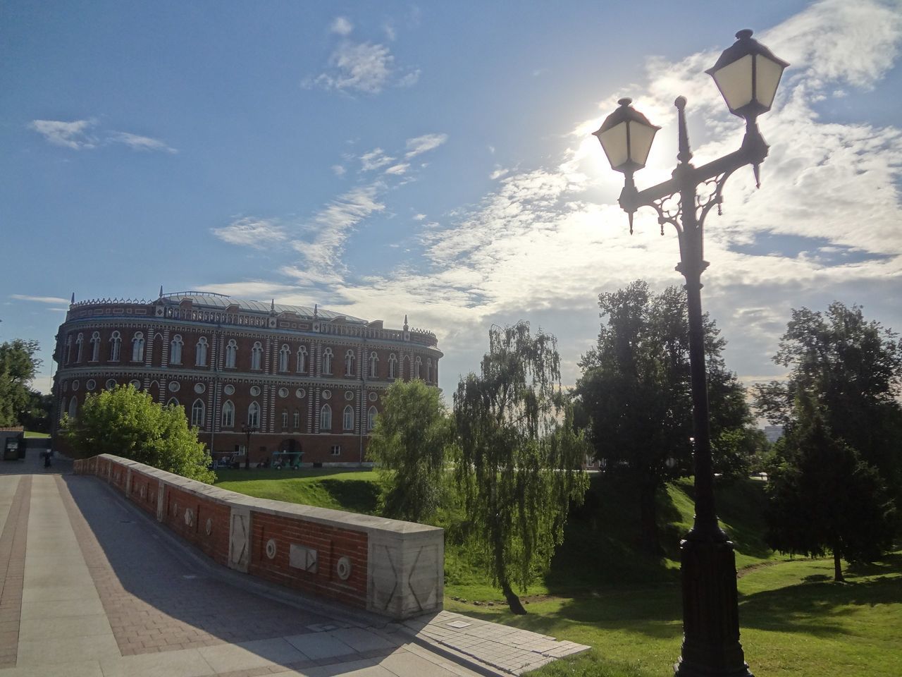 sky, tree, cloud, architecture, footpath, walkway, building exterior, garden, sunny, pedestrian walkway, day, park, pathway, formal garden, outdoors, memories, cloud - sky, lawn, signboard, hedge