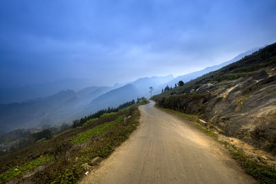 Road leading towards mountains against sky