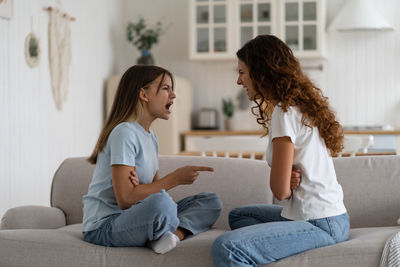 Young woman using mobile phone while sitting on bed at home