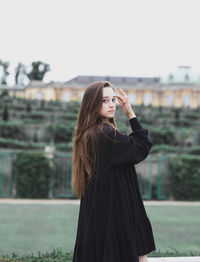 Woman looking away while standing against sky