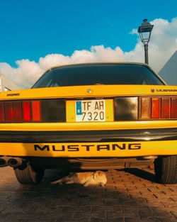Yellow car on road in city against sky