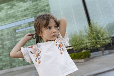 Portrait of a little girl outside in summer at glass building