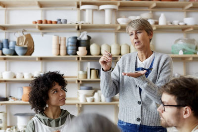 Mature female teacher explaining students in art class