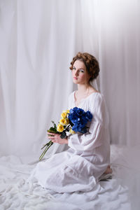 Ukrainian girl with blue yellow flowers in white