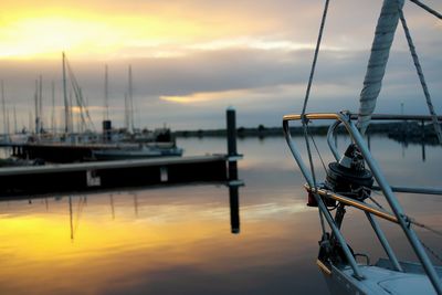 Boats moored at harbor against cloudy sky during sunset