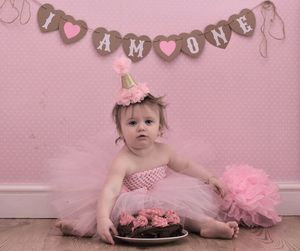 Portrait of baby girl with birthday cake sitting on floor at home