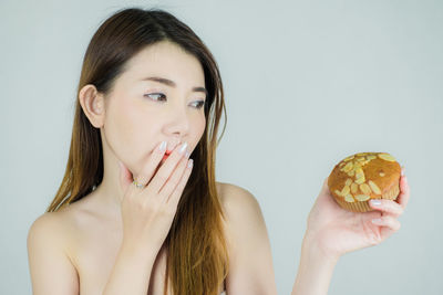 Portrait of woman holding ice cream against white background