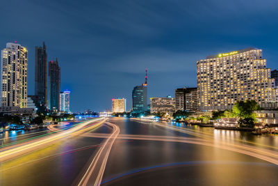 Light trails on road amidst buildings against sky in city