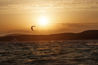 Scenic view of a kitesurfer in the sea against sky during sunset