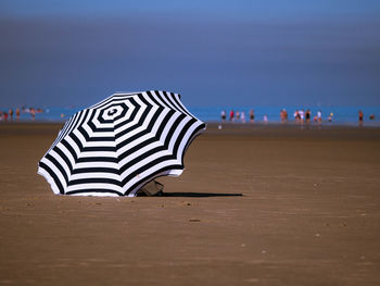 Striped parasol at beach against sky