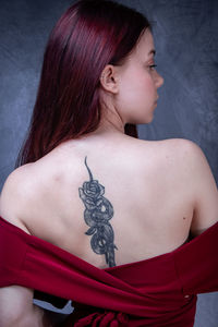 Portrait of young woman standing against wall