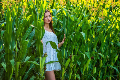 Portrait of young woman standing amidst plants