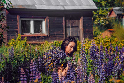 Woman standing by purple flowering plants