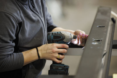 Woman using drilling machine in factory