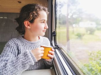 Young woman looking through window