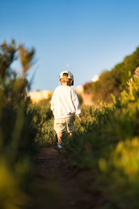 Rear view of child standing on land against sky