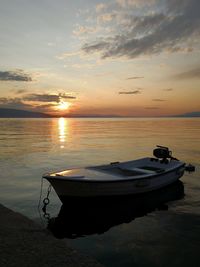 Boat moored on sea against sky during sunset