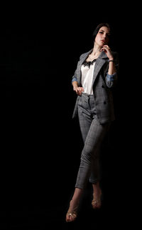 Woman looking away while standing against black background