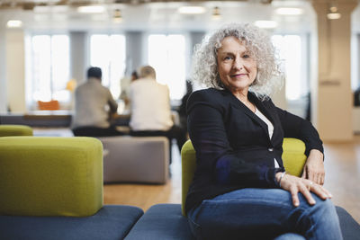 Portrait of senior woman sitting on couch at corridor