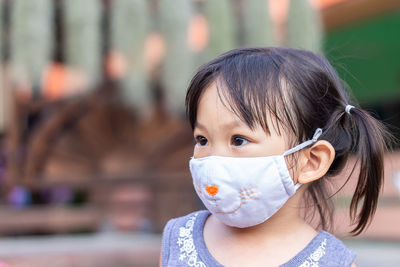 Close-up of girl wearing mask looking away