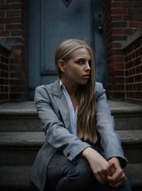 Young woman looking away while sitting on steps