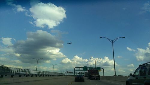 Cars on road against cloudy sky