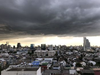 High angle view of buildings in city against storm clouds