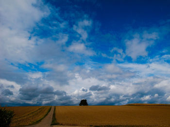 Scenic view of field against cloudy sky