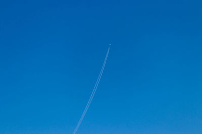 Low angle view of vapor trail against blue sky